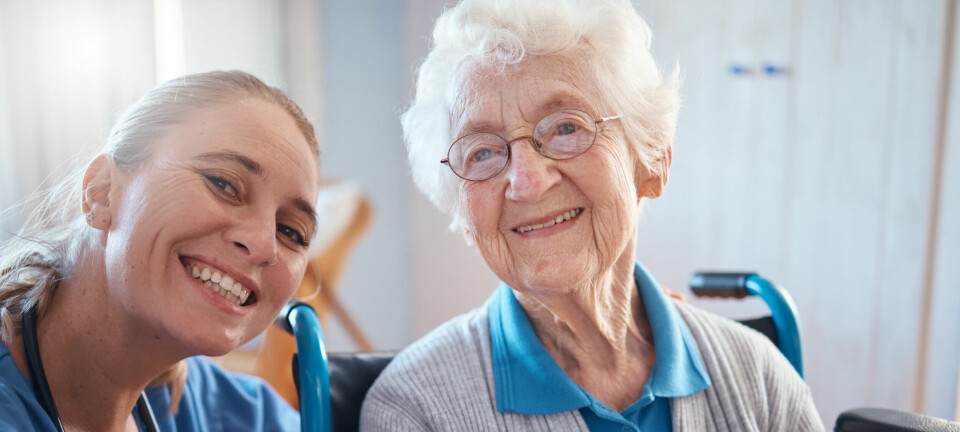 Kvinnelig sykepleier med eldre kvinnelig pasient, begge smilende