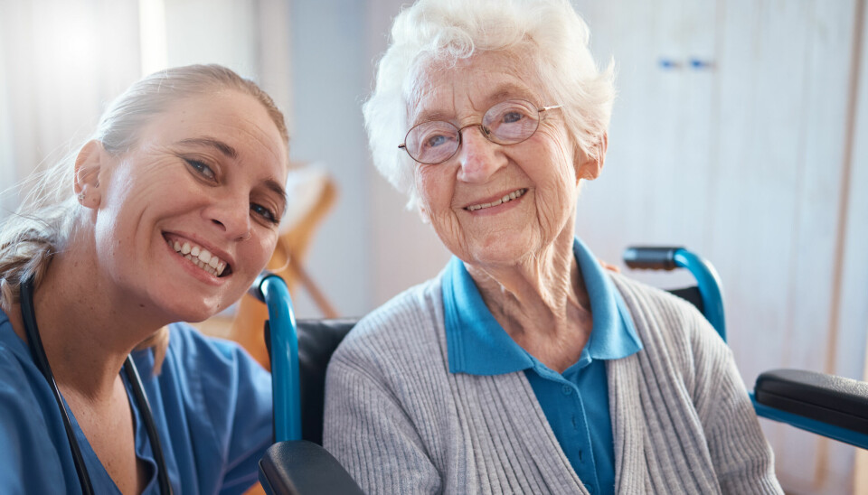 Kvinnelig sykepleier med eldre kvinnelig pasient, begge smilende