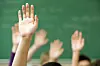 Flere oppstrakte hender foran en grønn tavle i et klasserom