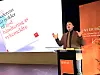Foredragsholder taler fra talerstol med Parat-logo og presentasjon på skjerm bak.