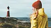 Jente i gul regnjakke med fyrtårn i bakgrunnen