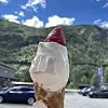 Is i kjeks med jordbær på toppen foran grønn fjellside