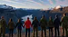 Gruppe mennesker ser utover et fjellandskap fra et utsiktspunkt.